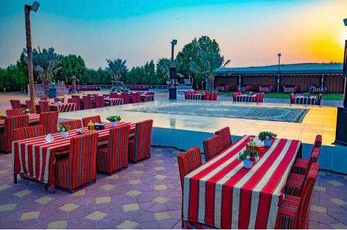 un patio con mesas y sillas rojas y una piscina en Desert Safari Dubai Tour Chemist en Dubái