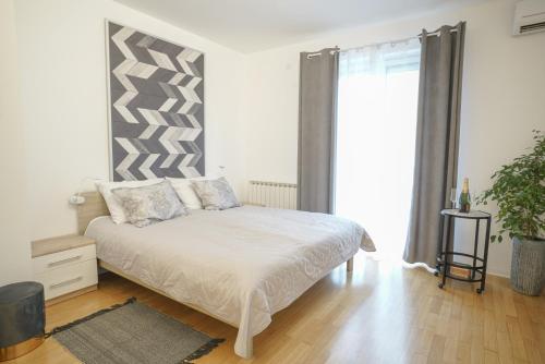um quarto branco com uma cama e uma grande janela em APARTIQUE ZAGREB studio apartman em Zagreb