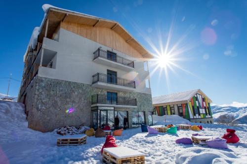 GeoGraphy Hotels في غودواري: مبنى في الثلج وخلفه الشمس