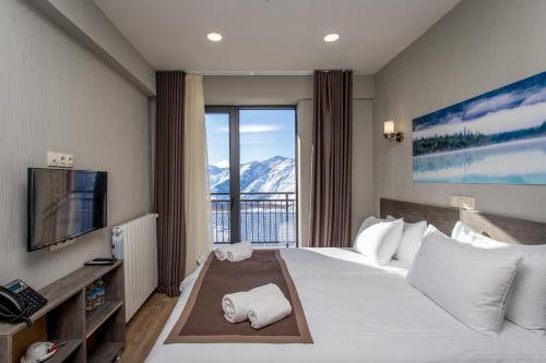 a hotel room with a large bed and a balcony at GeoGraphy Hotels in Gudauri