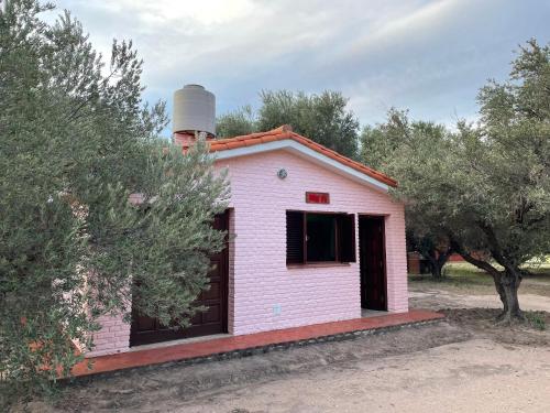 una casa rosa con una chimenea encima en Cabañas Puerta del Sol - San Marcos Sierras en San Marcos Sierras