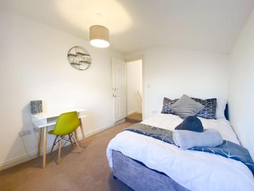 a bedroom with a bed and a desk with a green chair at Central 4 bed-Reading City Centre in Reading