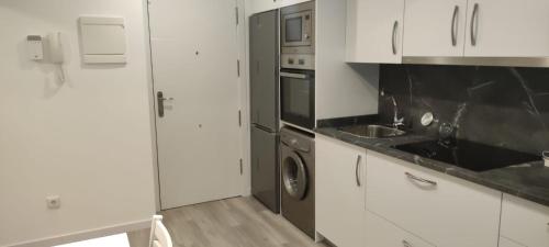 cocina con armarios blancos, fregadero y lavavajillas en Apartamento Mc Lion, en Alcobendas
