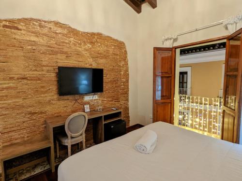 a bedroom with a bed and a desk and a tv at Catalina Suites in Valencia