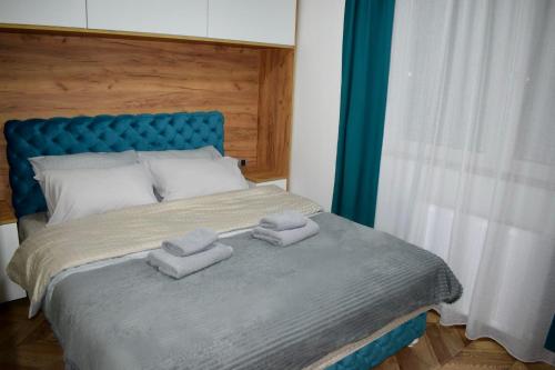 een slaapkamer met een blauw bed en handdoeken bij Pink House Apartments in Jagodina