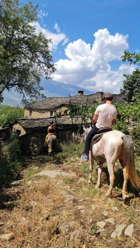 two people riding on horses in front of a building at Funky Guest House & Adventures in Përmet