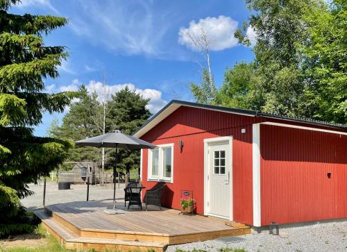 a red shed with a table and an umbrella at Annehill i Bro in Bro