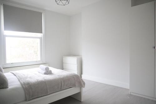 a white bedroom with a bed and a window at Twelve Thirty Serviced Apartments - 2 Croydon in South Norwood