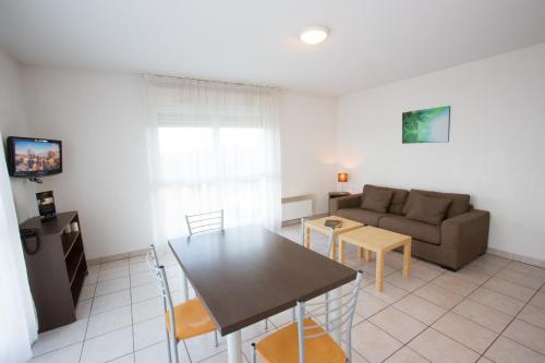 a living room with a table and a couch at All Suites Appart Hôtel - Bordeaux - Mérignac Aéroport in Mérignac