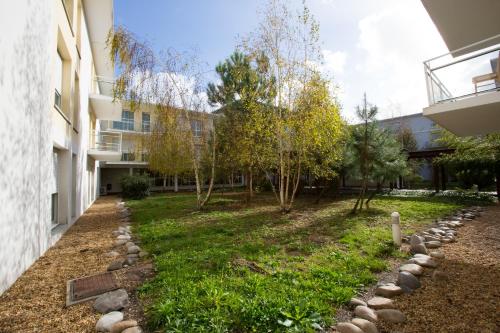 a courtyard of a building with trees and rocks at All Suites Appart Hôtel - Bordeaux - Mérignac Aéroport in Mérignac