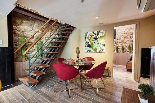 a dining room with a table and red chairs and a spiral staircase at AmazINN Places Rooftop and Design Pool X in Panama City