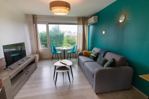 a living room with a couch and a tv and a table at Le Pic'Vert de Bergerac - Studio - Au calme - Parking gratuit - Fibre in Bergerac