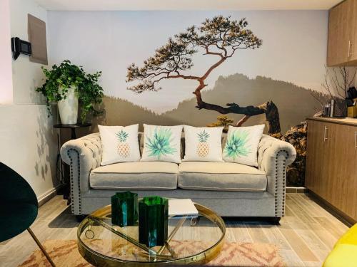 a living room with a couch with a tree on the wall at AmazINN Places Casco Viejo Duplex and Pool in Panama City