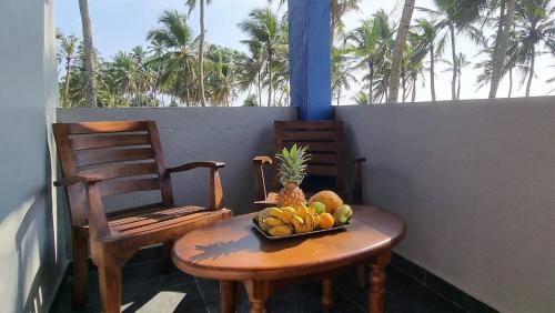 ワドゥワにあるDhammika Beach Palaceの椅子2脚付きのテーブルに果物を盛り付けます。