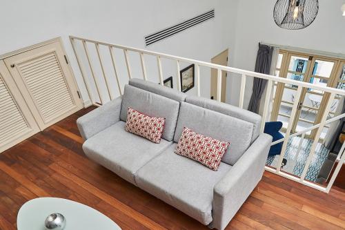 a living room with a gray couch with two pillows at AmazINN Places Casco Viejo Casa Boyd in Panama City
