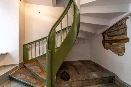 a green spiral staircase in a house with a stone wall at Roofs of the Old Tallinn Guest House in Tallinn