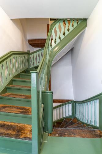 a staircase in a building with green railings at Roofs of the Old Tallinn Guest House in Tallinn