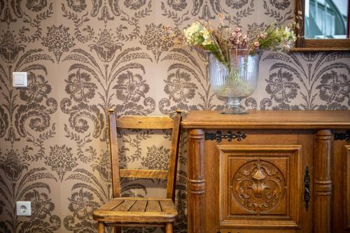 a chair and a vase with flowers on a wall at Roofs of the Old Tallinn Guest House in Tallinn