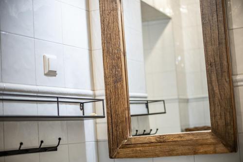 a mirror with a wooden frame in a bathroom at Roofs of the Old Tallinn Guest House in Tallinn