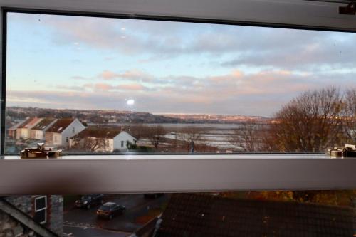 a view of a city from a window at Extended Fishermans cottage with stunning sea views in The Mumbles