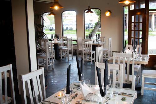 une salle à manger avec des tables blanches, des chaises et des fenêtres dans l'établissement Darwin Hotel, à Puerto Natales