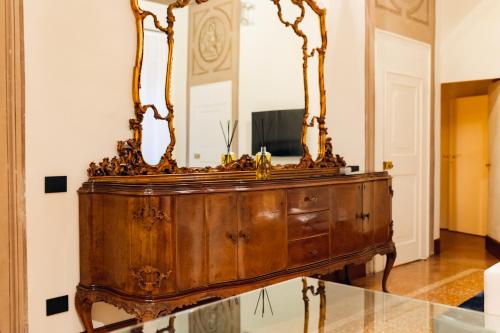 an antique dresser in a room with a mirror at [Private Parking] centro storico: l'affresco in Bologna