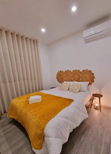 a bedroom with a large bed with a yellow blanket at VILLAS com piscina in Vila Nova de Gaia