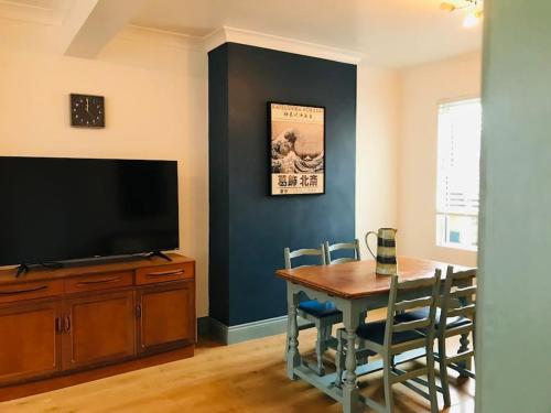 a dining room with a table and a flat screen tv at Spacious 3 bed house near beach! in Lowestoft