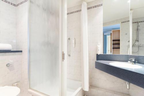 a bathroom with a shower and a sink and a mirror at Holiday Inn Express Park Royal by IHG in London