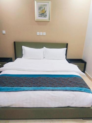 una camera da letto con un grande letto con lenzuola e cuscini bianchi di الياسمين للشقق المفروشة a Gedda