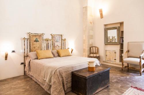 a bedroom with a large bed and a chair at Antica Dimora Giardini Segreti in Giuggianello