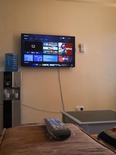 a tv on a wall with a remote control on a bed at Bamburi BnB in Mombasa