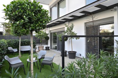 einen Garten mit Stühlen, einem Tisch und einem Baum in der Unterkunft The Lop Athens Holidays Luxury Suites in Athen