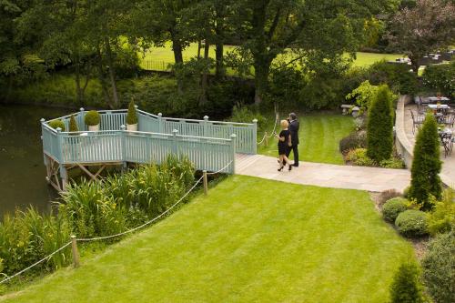 a man and woman walking on a walkway in a garden at Whitley Hall Hotel in Chapeltown