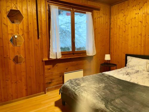 een slaapkamer met een bed en een raam bij L'appel Chalet in Choex