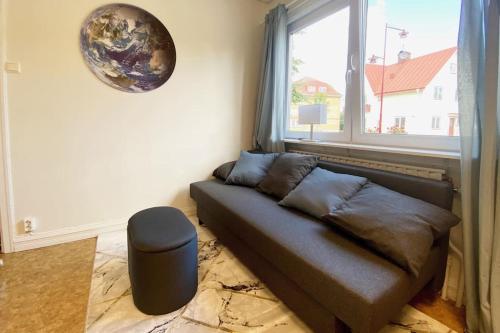 a couch in a living room with a window at central apartment with free parking in Huskvarna