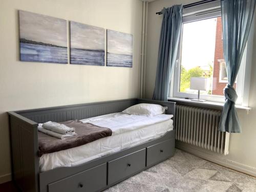 a bed in a bedroom with a window and a bed frame at central apartment with free parking in Huskvarna