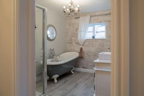 ein Badezimmer mit einer Badewanne, einem Waschbecken und einem Spiegel in der Unterkunft Charming 2 Bed House in Tewkesbury Centre in Tewkesbury