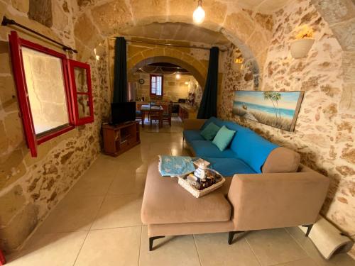 - un salon avec un canapé bleu dans un mur en pierre dans l'établissement Gozo Sunset Farmhouse, à Qala