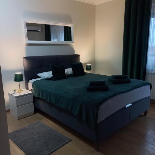 - une chambre avec un grand lit et une couverture verte dans l'établissement Apartman Lola, à Subotica