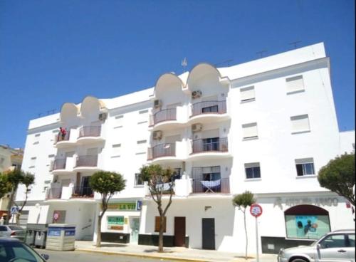 un edificio blanco con balcones en una calle en CHIPIONA SOL Y PLAYA, en Chipiona