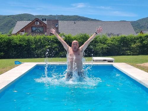 un hombre en una piscina con sus brazos en el aire en Suites del Sol en Villa General Belgrano