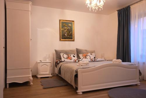ein Schlafzimmer mit einem weißen Bett und einem Kronleuchter in der Unterkunft casa Flav in Iaşi