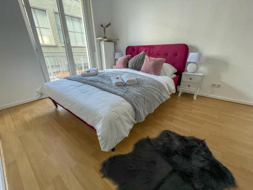 1 dormitorio con 1 cama grande y cabecero rosa en UrbanSuites - Stylish Apartments I Koblenz Center I Kitchen I up to 115m2 en Coblenza