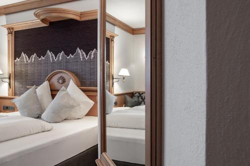 a mirror in a hotel room with two beds at Hotel Glöckner und Hotel Residenz Glöckner in Ischgl