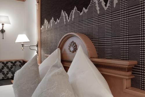 a wooden headboard with white pillows on a bed at Hotel Glöckner und Hotel Residenz Glöckner in Ischgl