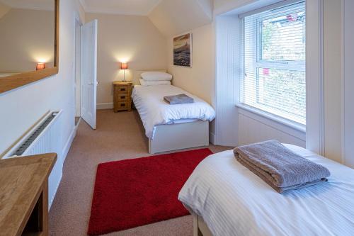 a small room with two beds and a red rug at Edengrove in Aberfeldy