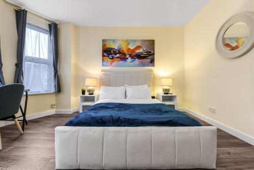 a bedroom with a large bed with a blue blanket at Near Canada Water, 2 Beds, Families, Overground in London