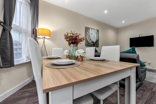 a dining room with a wooden table and white chairs at Near Canada Water, 2 Beds, Families, Overground in London