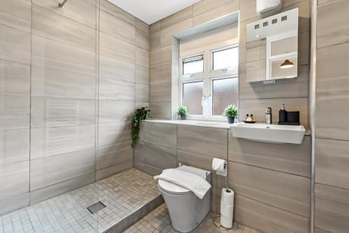 a bathroom with a toilet and a window at Near Canada Water, 2 Beds, Families, Overground in London